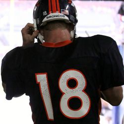 Peyton Manning straps on his helmet before making his way to the field before the summer scrimmage