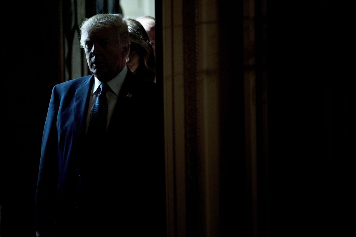Donald Trump standing in the doorway of a dark room.