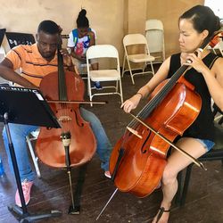 Utah Symphony cellist Anne Lee providing one-on-one instruction for a young Haitian musician.