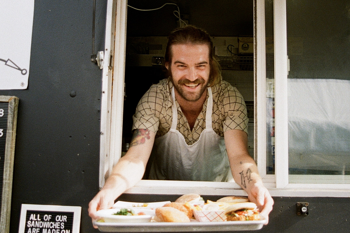 Brad Dodson holds out a tray of bolo levedo sandwiches at the Bolo food cart.