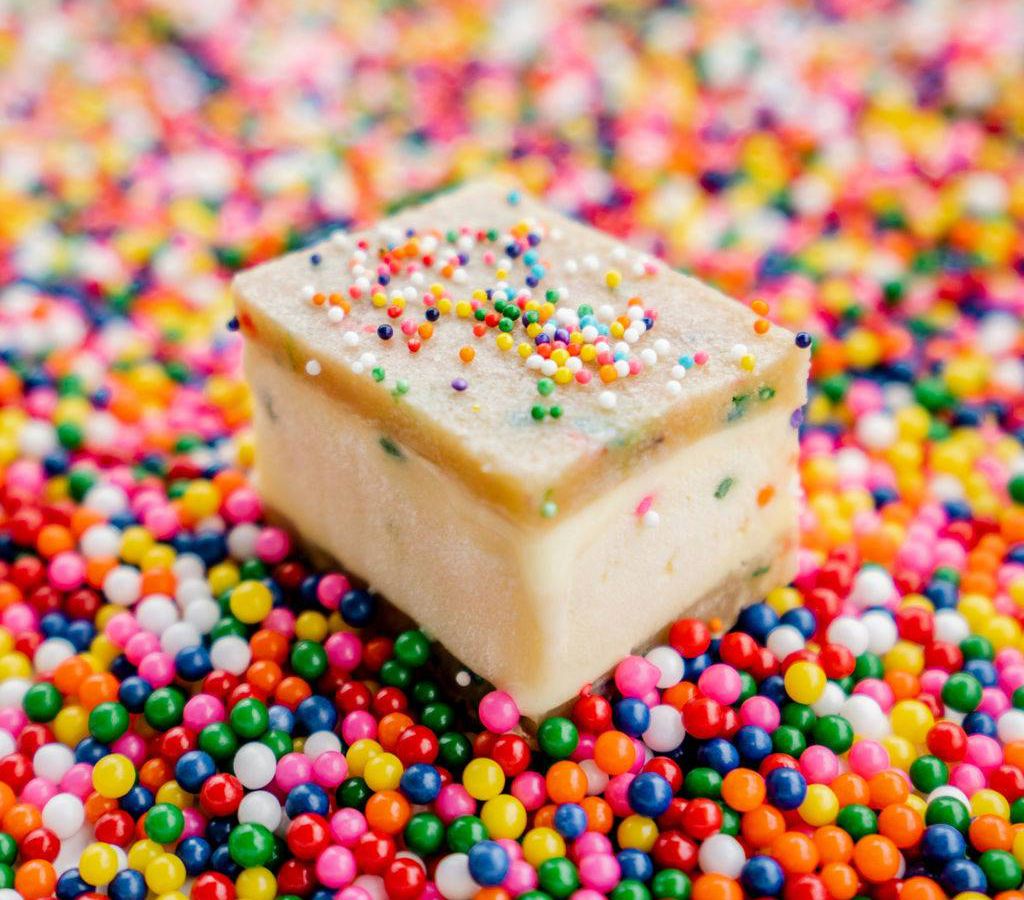 A birthday cake ice cream sandwich on a bed of colorful sprinkles