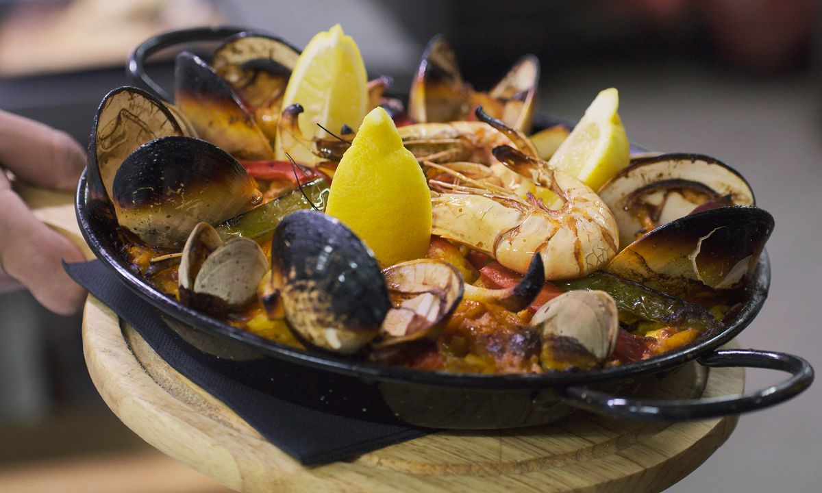 A black dish of shellfish presented on a tray. 
