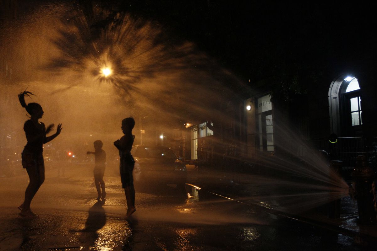 People cool off at an open fire hydrant in the East Village neighborhood of Manhattan.