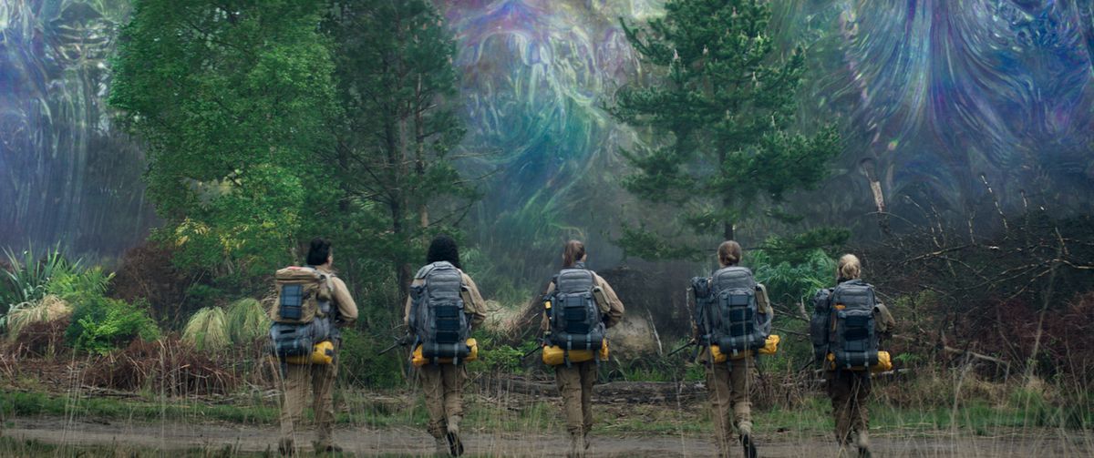 Four women in hiking gear and holding rifles prepare to cross through the rainbow shimmer in Annihilation 