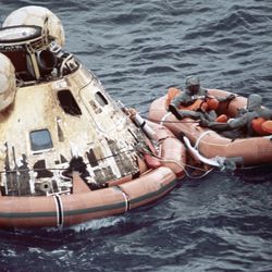 U.S. Navy personnel, protected by Biological Isolation Garments, are recovering the Apollo 11 crew from the re-entry vehicle, which landed safely in the Pacific Ocean on July 24, 1969, after an eight-day mission on the moon.