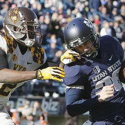 Wyoming's Marqueston Huff grabs USU's Jaron Bentrude by the face mask as Utah State and Wyoming play Saturday, Nov. 30, 2013, in Logan.