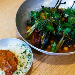 A stew with tomato, poached fish, and mussels, with a side of housemade couscous and pumpkin tershi