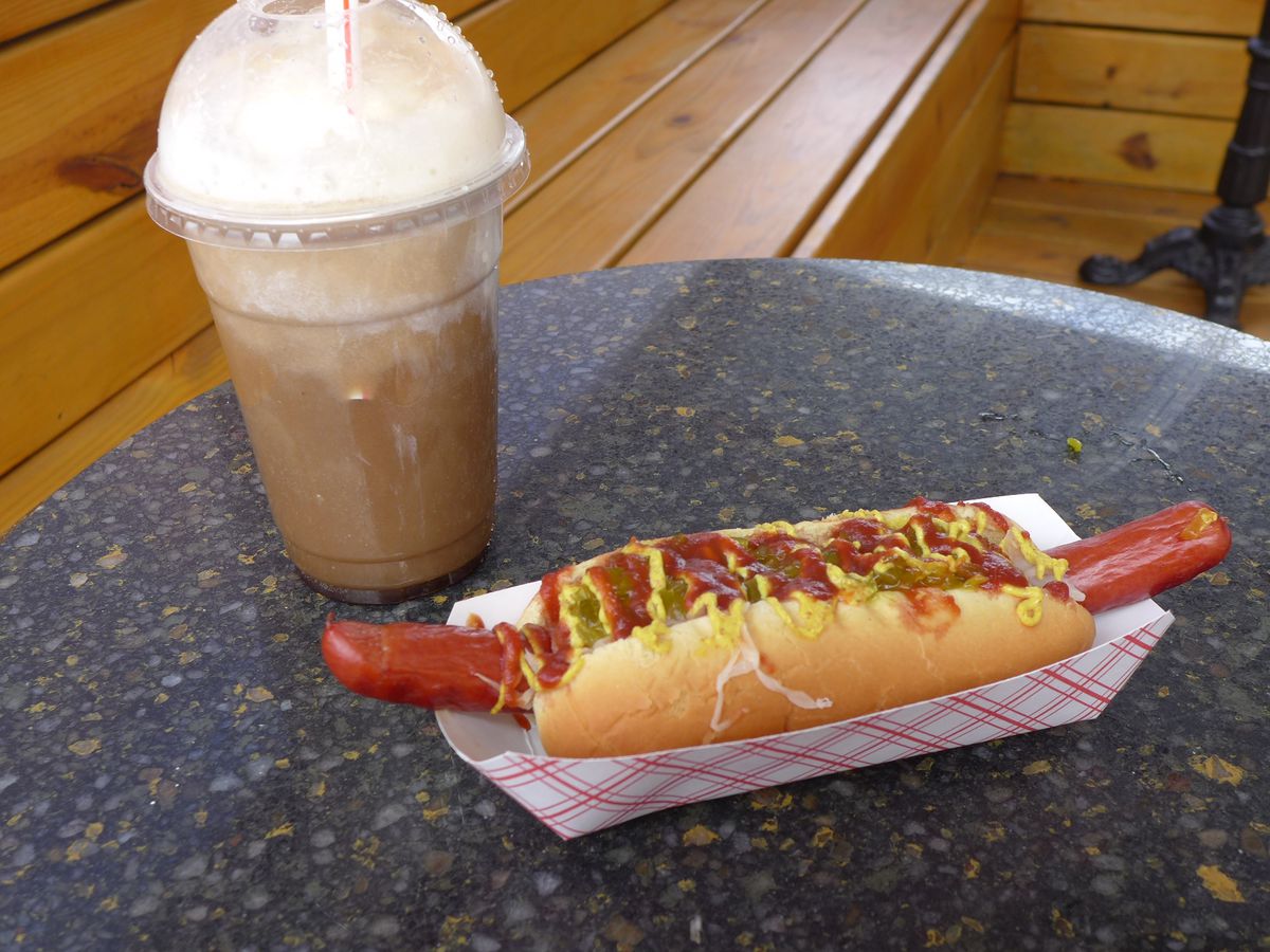 A hot dog flops out of the bun on both ends, plus a foamy root beer float.
