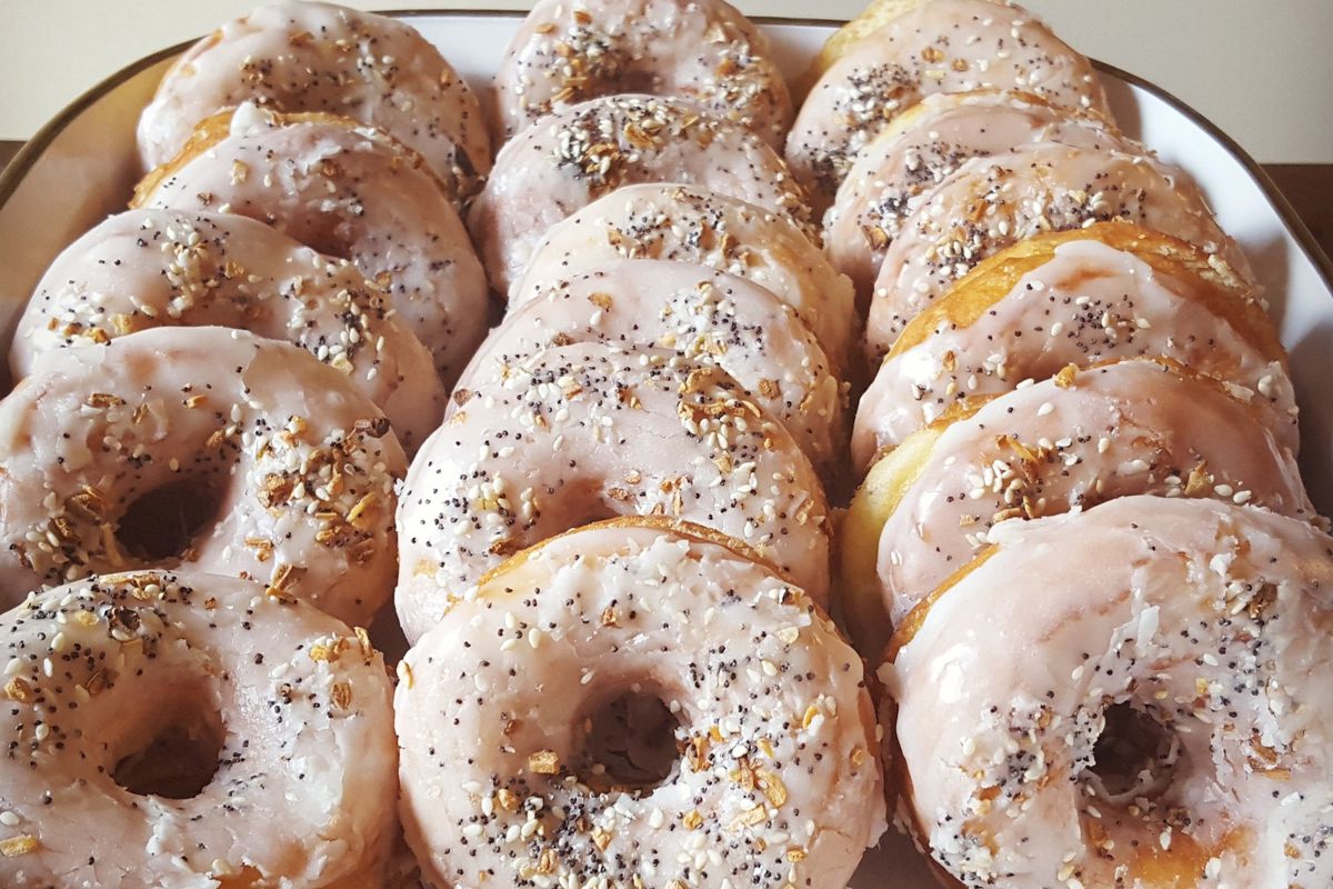 Rows of vanilla glazed doughnuts topped with poppyseeds and more
