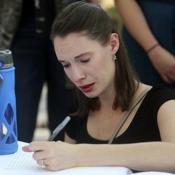 A woman writes a note during a vigil for Mackenzie Lueck, a University of Utah student believed to have been murdered, on the University of Utah Union lawn in Salt Lake City on Monday, July 1, 2019.