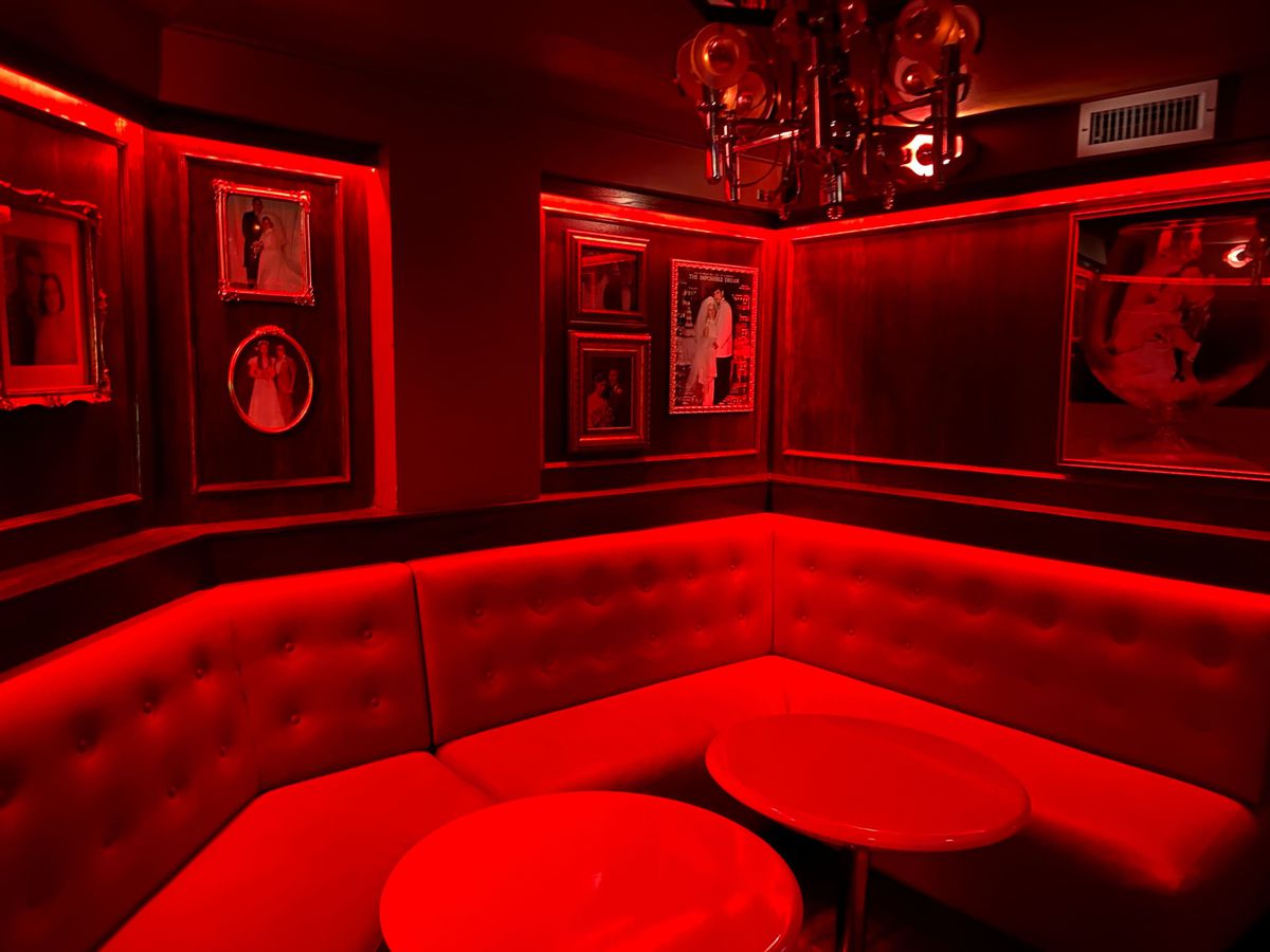 A red-lit bar booth with two tables.
