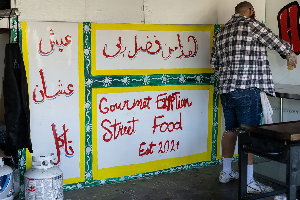 Arabic signage inside of a garage as a man is cooking.