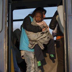 A UNHCR worker takes a toddler onto the bus heading to the Moria camp, after he and other migrants were rescued by the Greek coast guard off the coast of the Greek island of Lesbos, on Monday, March 21, 2016. The number of stranded migrants in Greece exceeded 50,000 Monday as the number of daily arrivals showed no sign of dropping. 
