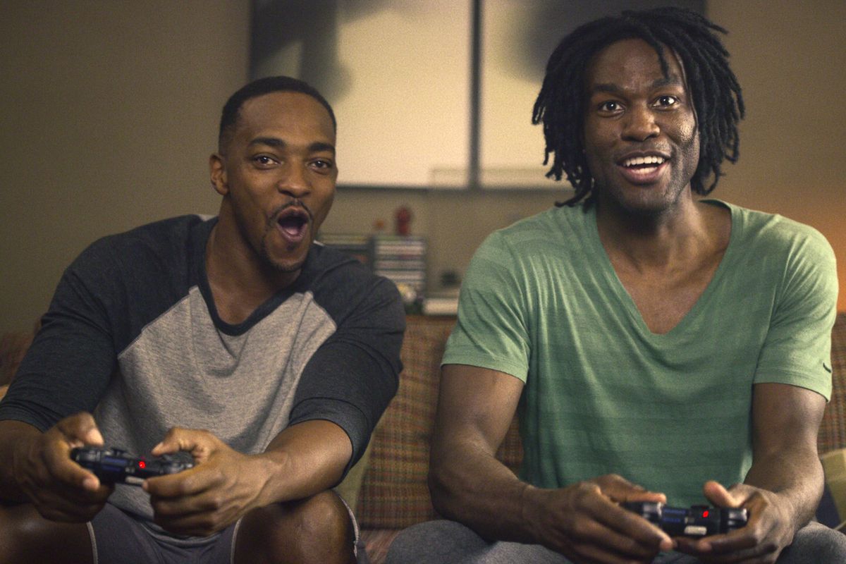 Danny (Anthony Mackie) and Karl (Yahya Abdul-Mateen II) playing video games on a couch.