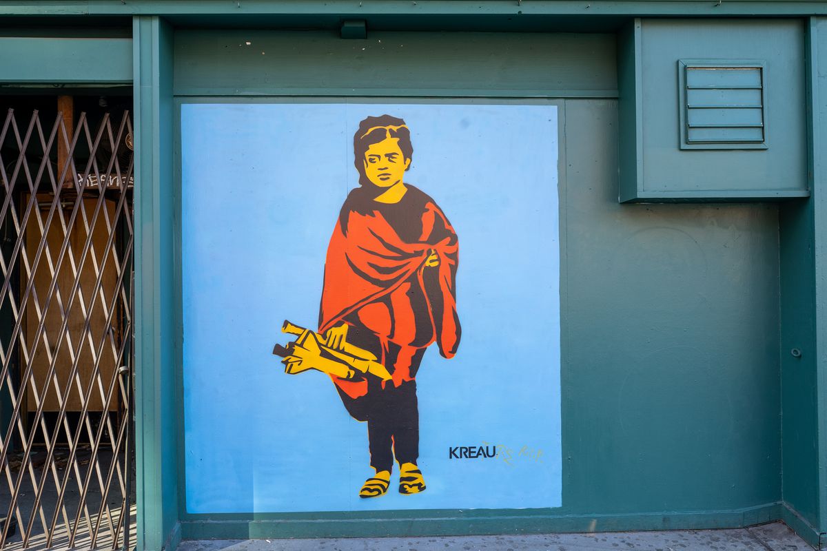 A mural painted on a teal-blue wall of a woman or girl holding a toy rocket, dressed in a red robe.