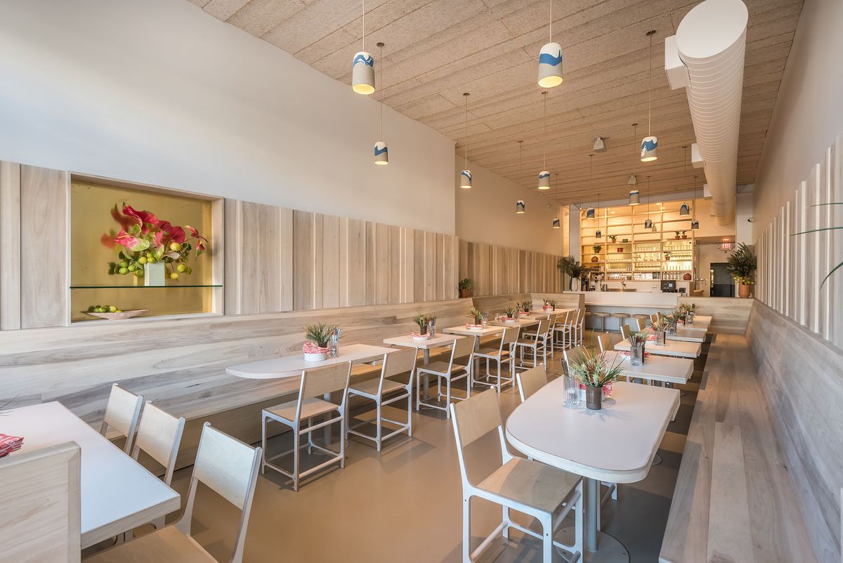 A beachy, gray wood dining room featuring rows of empty tables and built-in seating.