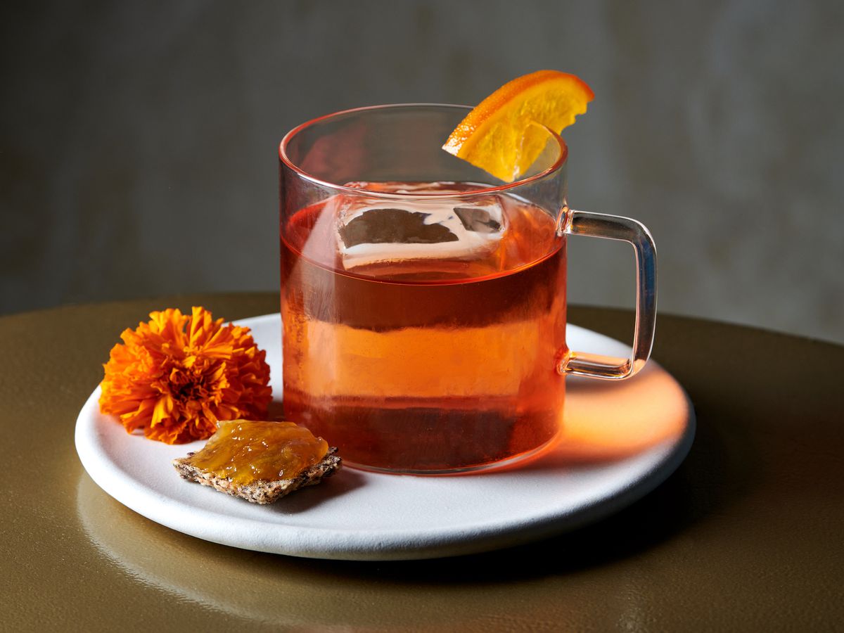 A clear glass of tea with alcohol infusion set on a white plate.