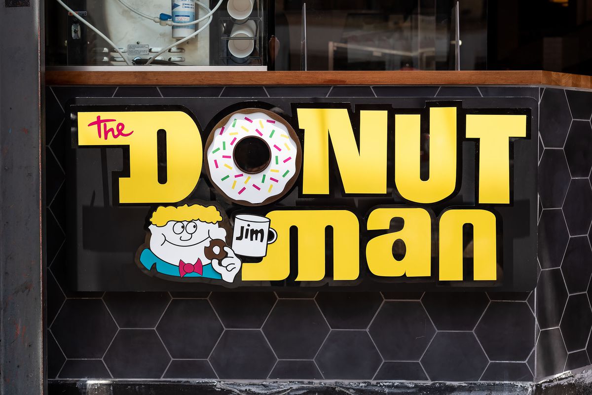 The sign for the Donut Man, a golden logo with a person holding a coffee mug.