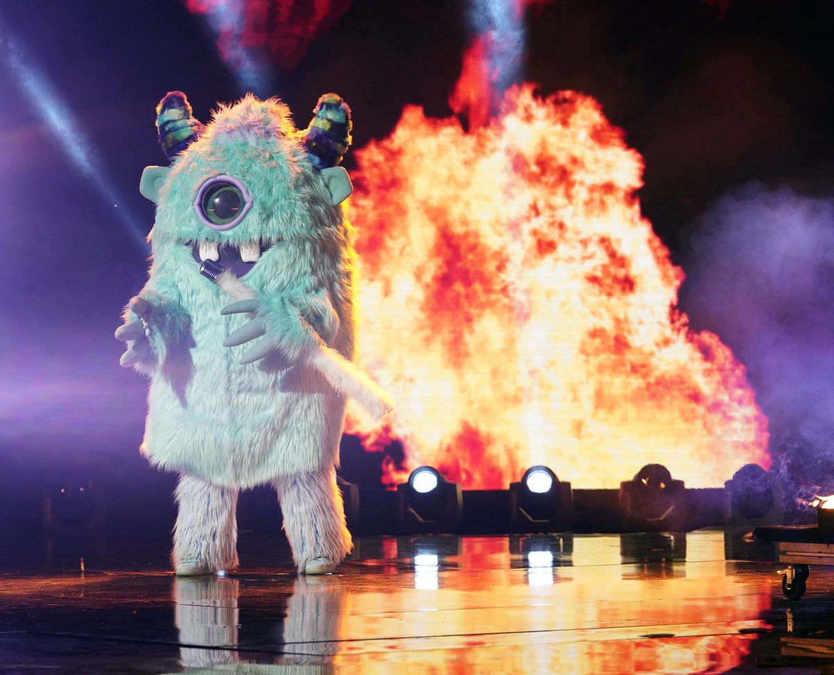The monster singer standing on stage in front of a fire