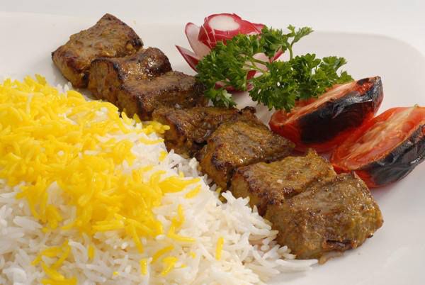 Beef kabob with rice and grilled tomatoes.