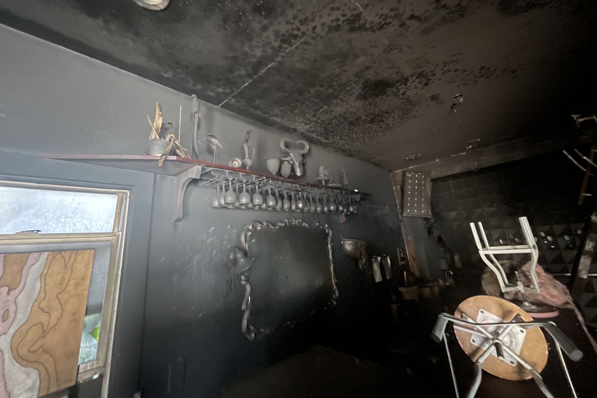 A smoke-damaged cafe with wine glasses hanging above the bar.