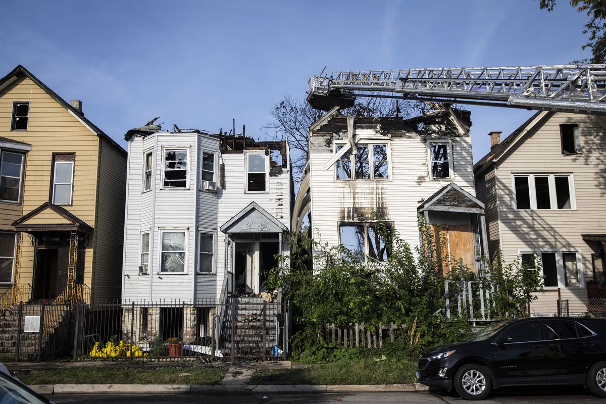 Chicago Fire Department firefighters work to extinguish hot spots Thursday morning after an overnight fire broke out in a vacant building and spread to six other buildings, including two coach houses, in the 4900 block of South Princeton Avenue in Fuller Park on the South Side.