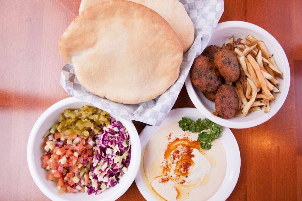A top-down view of pitas at Eggs and Plants, with falafel. Israeli salad, and hummus on the side.