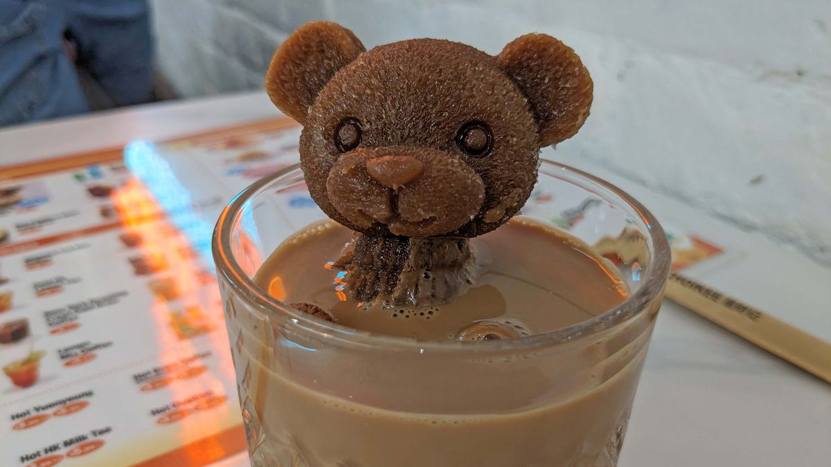 An ice cube bear sticks out of a cup of tea.