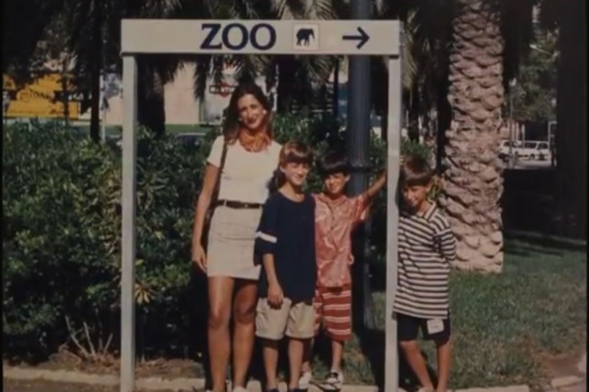 Daphne Caruana Galizia standing in front of a sign that says “Zoo” with her three young sons