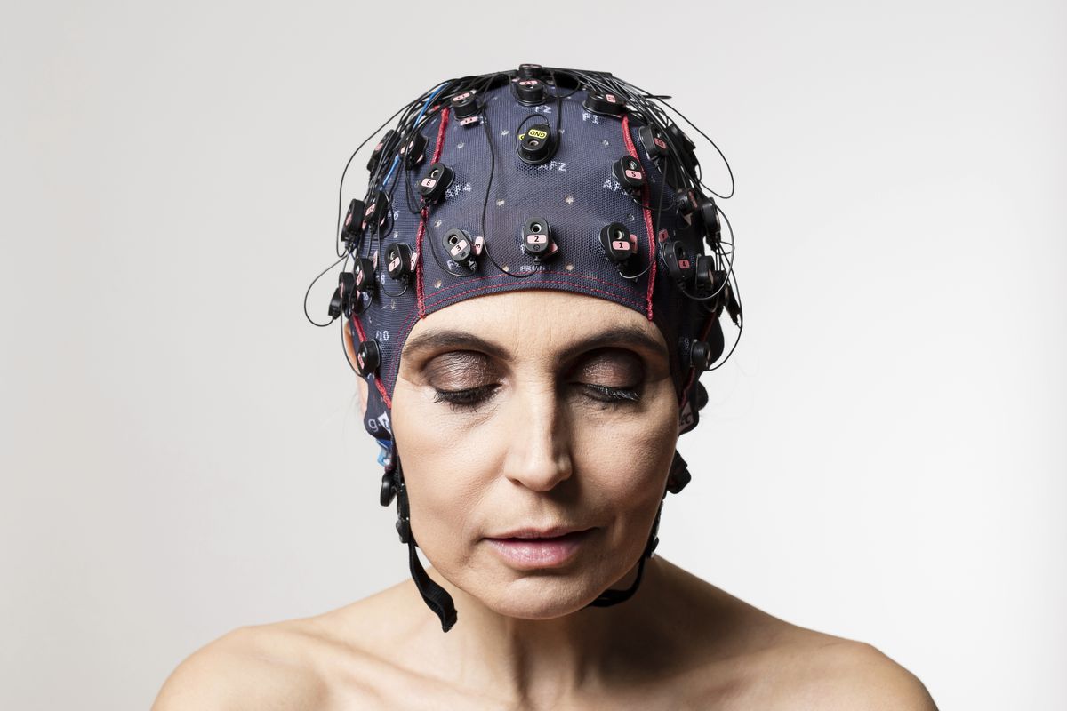 A woman equipped with a brain-computer interface that she is wearing as a bathing-suit-style cap on her head.