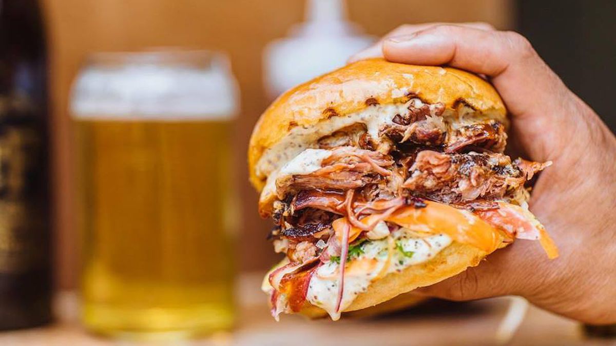 A hand holds a pulled pork sandwich