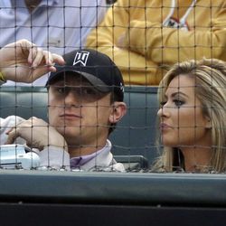 FILE - In this April 14, 2015, file photo, Cleveland Browns quarterback Johnny Manziel, left, sits with Colleen Crowley during a baseball game between the Los Angeles Angels and the Texas Rangers in Arlington, Texas. Prosecutors say they have an agreement with Johnny Manziel to dismiss a domestic violence charge against the Heisman Trophy-winning quarterback. The Dallas County District Attorney’s Office said Friday, Dec. 2, 2016, that Manziel will have to meet certain conditions for a year before the misdemeanor charge will be dismissed. The former Cleveland Browns player was accused of hitting and threatening former girlfriend Colleen Crowley during a night out in January. 