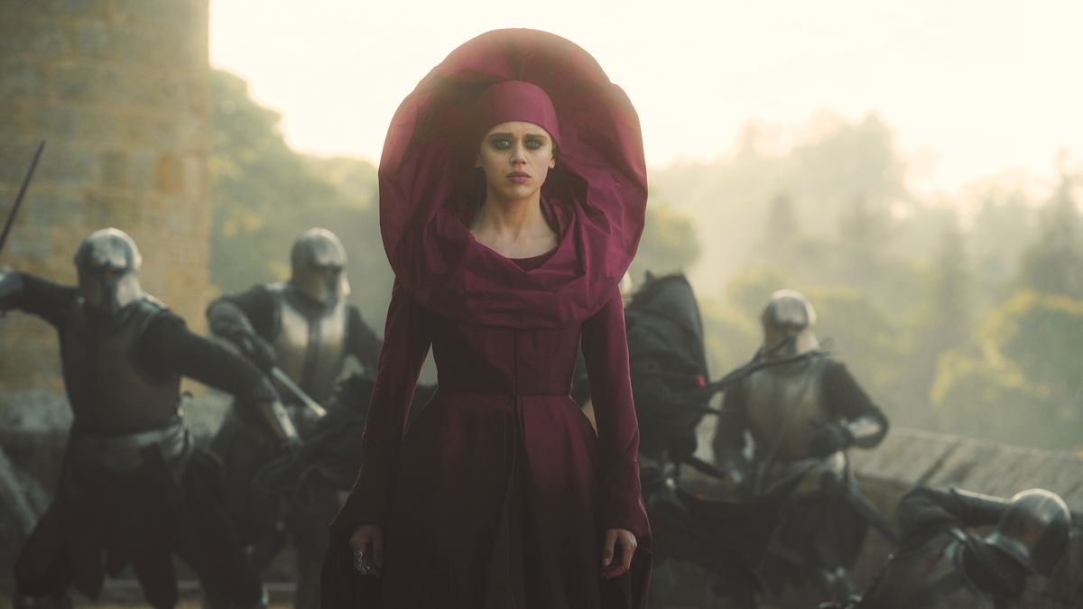 Daisy Head as Sofina, a Red Wizard of Thay in Dungeons &amp; Dragons: Honor Among Thieves. She wears a long dress and skullcap tinged a telltale red, as she walks impassively away from the fight that’s broken out behind her. 