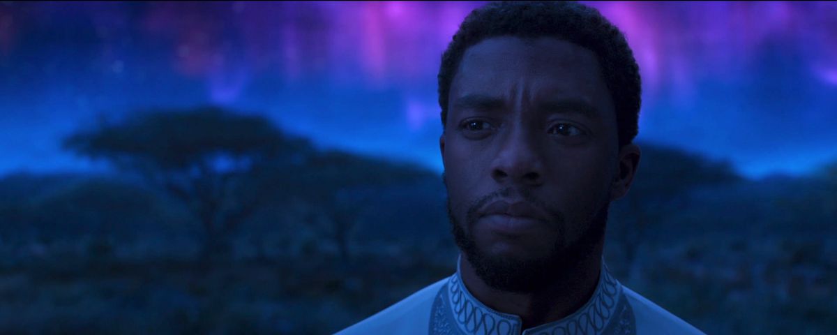 T’Challa (Chadwick Boseman) stands in front of the dark landscape and glowing pink-and-purple light of the Ancestral Plane in 2018’s Black Panther