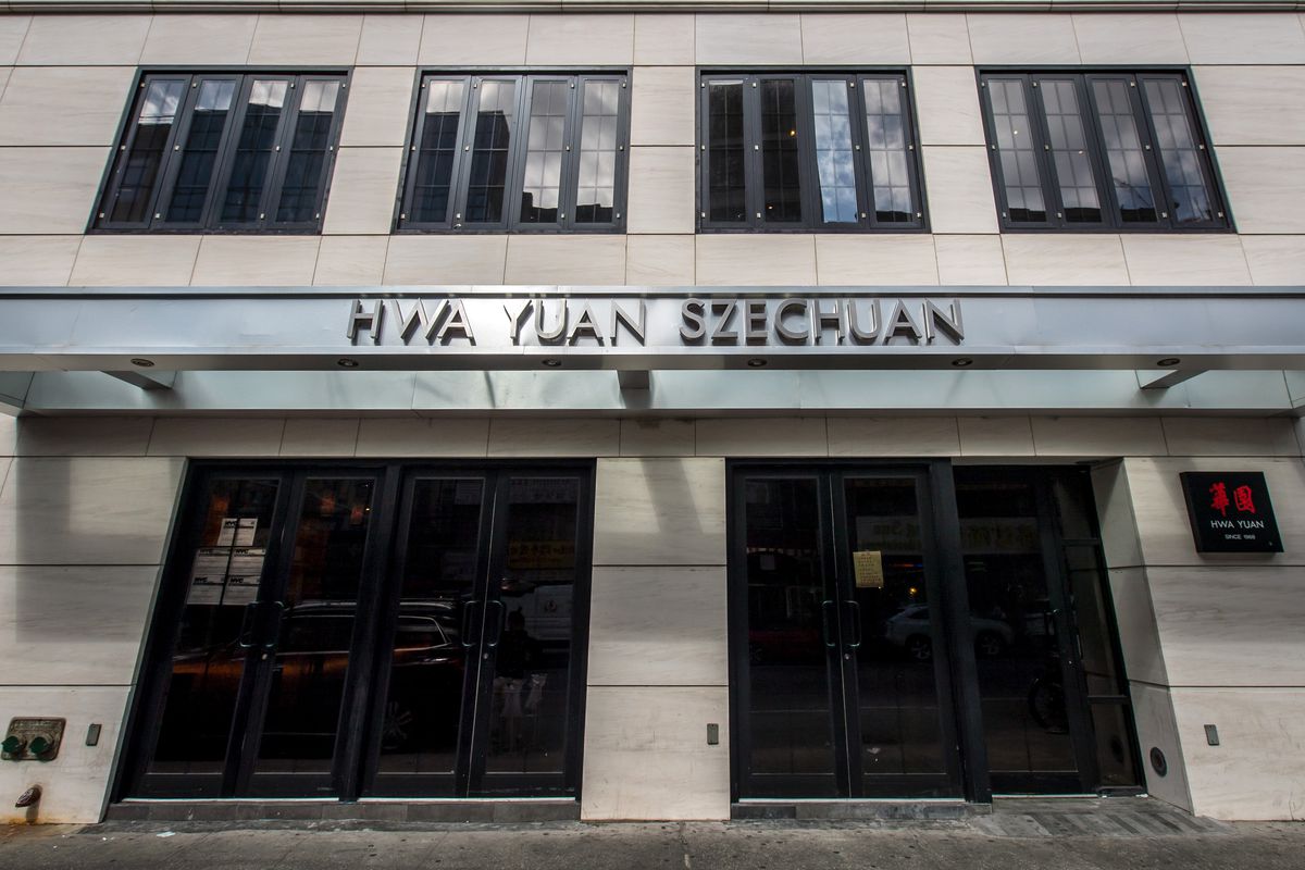 An exterior photo of Sichuan restaurant Hwa Yuan which shows a white stone exterior and a silver sign that bears the name.