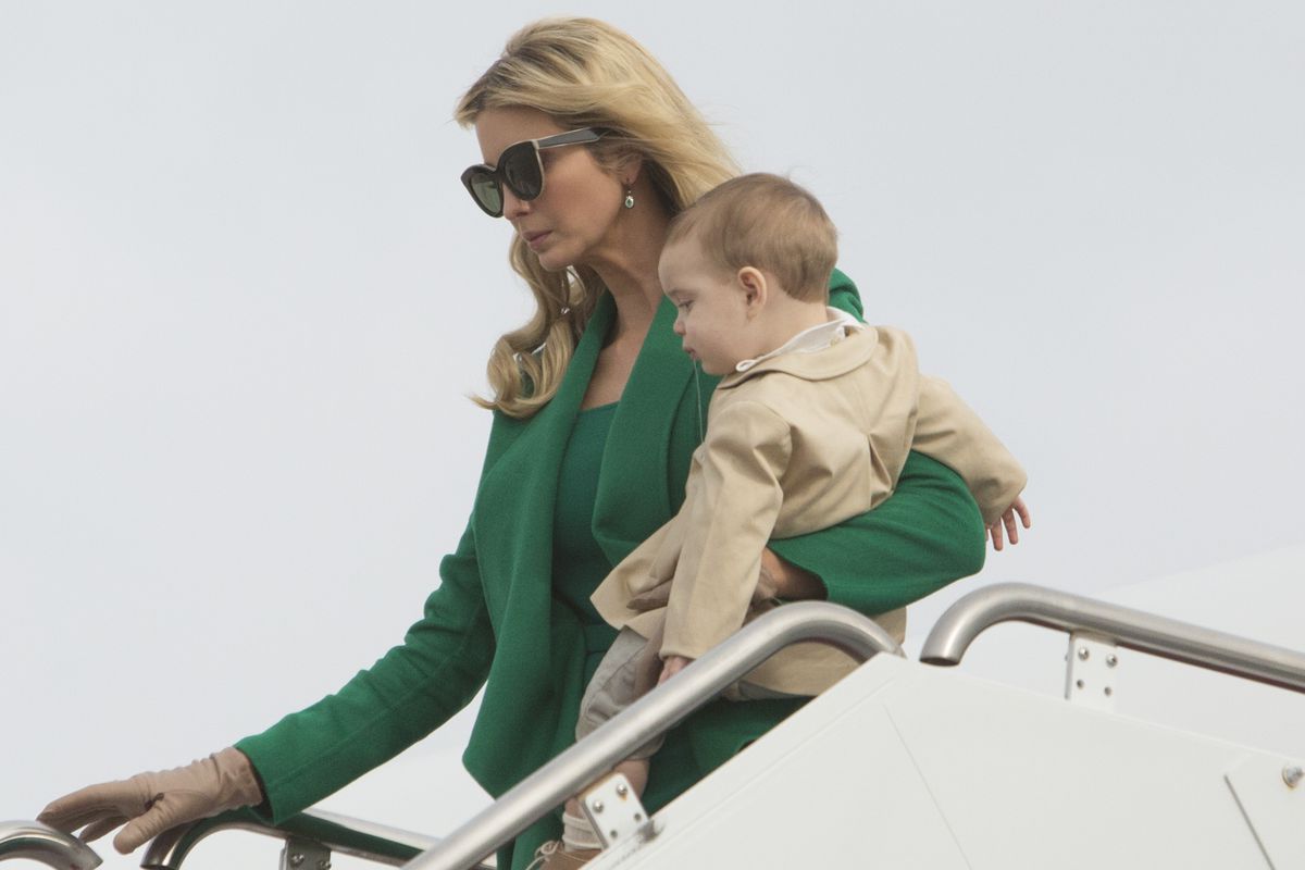 Ivanka Trump disembarking a plane wearing sunglasses while carrying her toddler