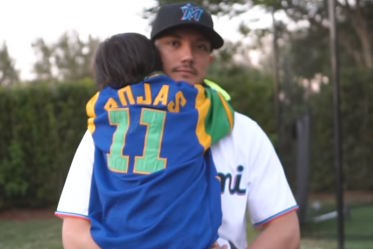Miguel Rojas holds his son, Aaron Rojas, who’s wearing a baseball jersey with the number 11