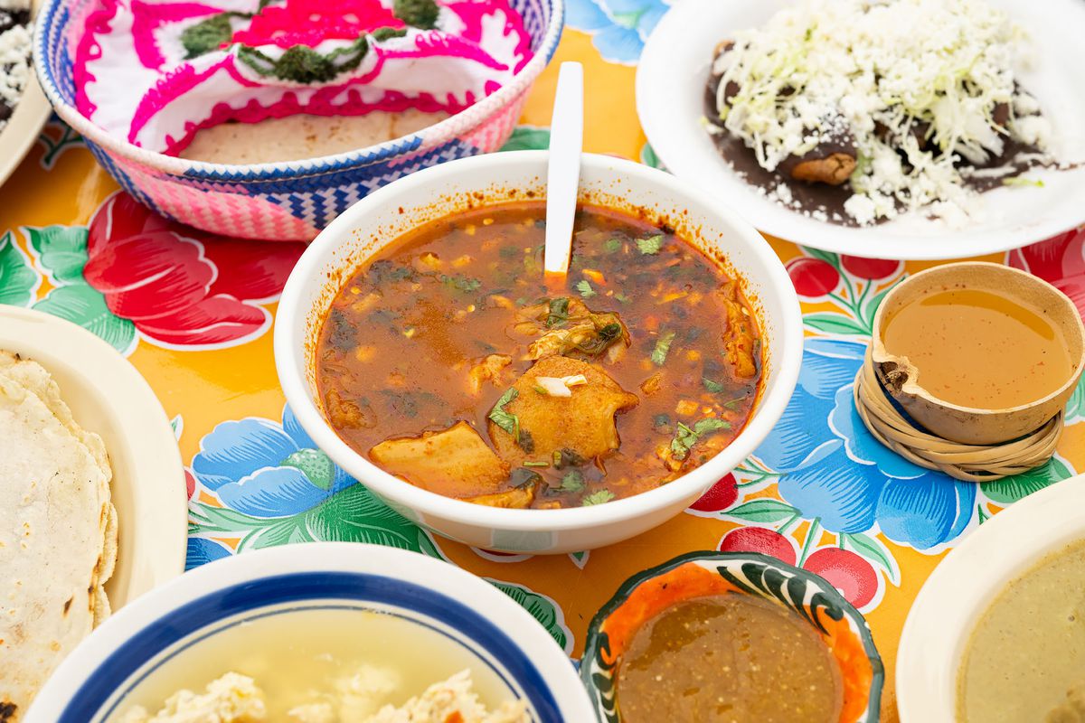 Menudo and other dishes from Comedor Tenchita served up together on a floral-print table.
