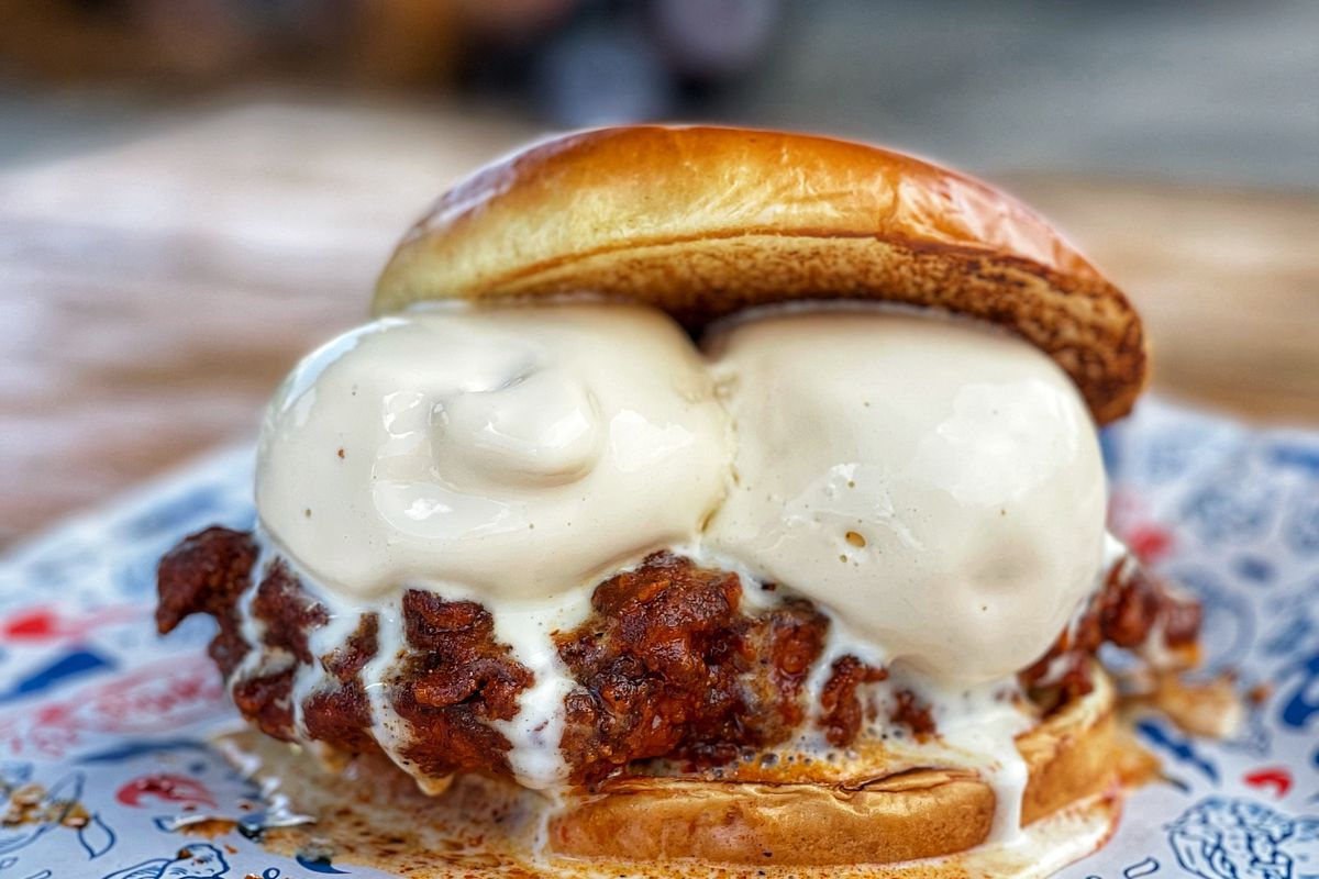 A chicken sandwich topped with two scoops of vanilla ice cream 