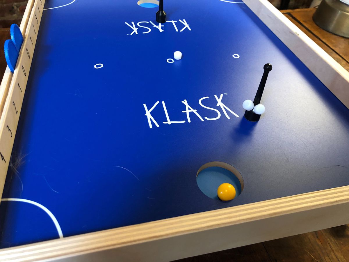 A Klask board with two biscuits attached to the striker