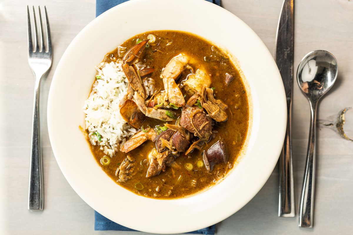 Gumbo is served in a white bowl with silver place settings.