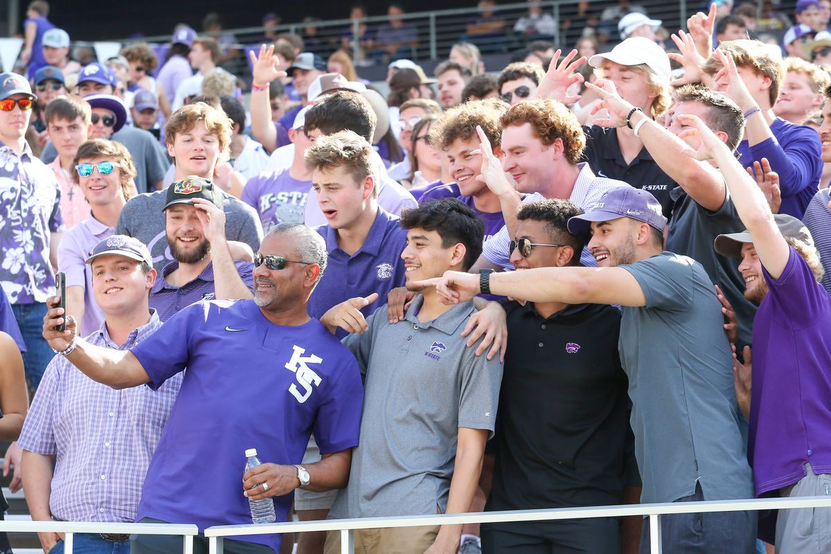 Background:&nbsp;Sep 9, 2023; Manhattan, Kansas, USA; Kansas State Wildcats head basketball coach (bottom left) takes a selfie with fans in the student section before the start of a football game between Kansas State Wildcats and the Troy Trojans at Bill Snyder Family Football Stadium. Mandatory Credit: Scott Sewell