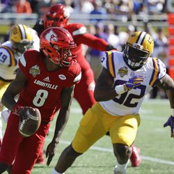 File-This Dec. 31, 2016, file photo shows Louisville quarterback Lamar Jackson (8) scrambling for yardage as he is pressured by LSU defensive end Lewis Neal (92) during the first half of the Citrus Bowl NCAA football game in Orlando, Fla. Jackson was named to the second team AP Preseason All-America Team on Tuesday, Aug. 22, 2017. 