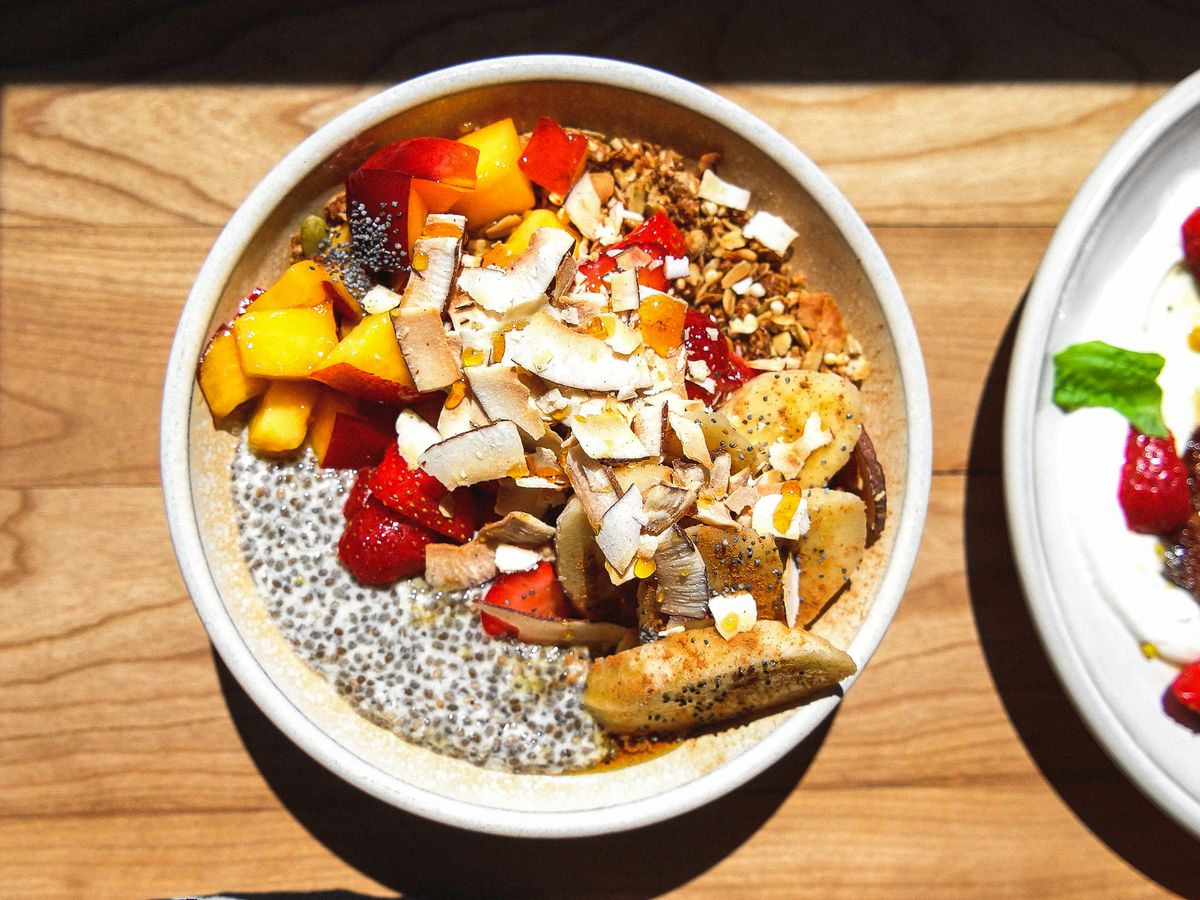 A bowl of chia pudding topped with sliced fruit, coconut, and nuts and seeds.