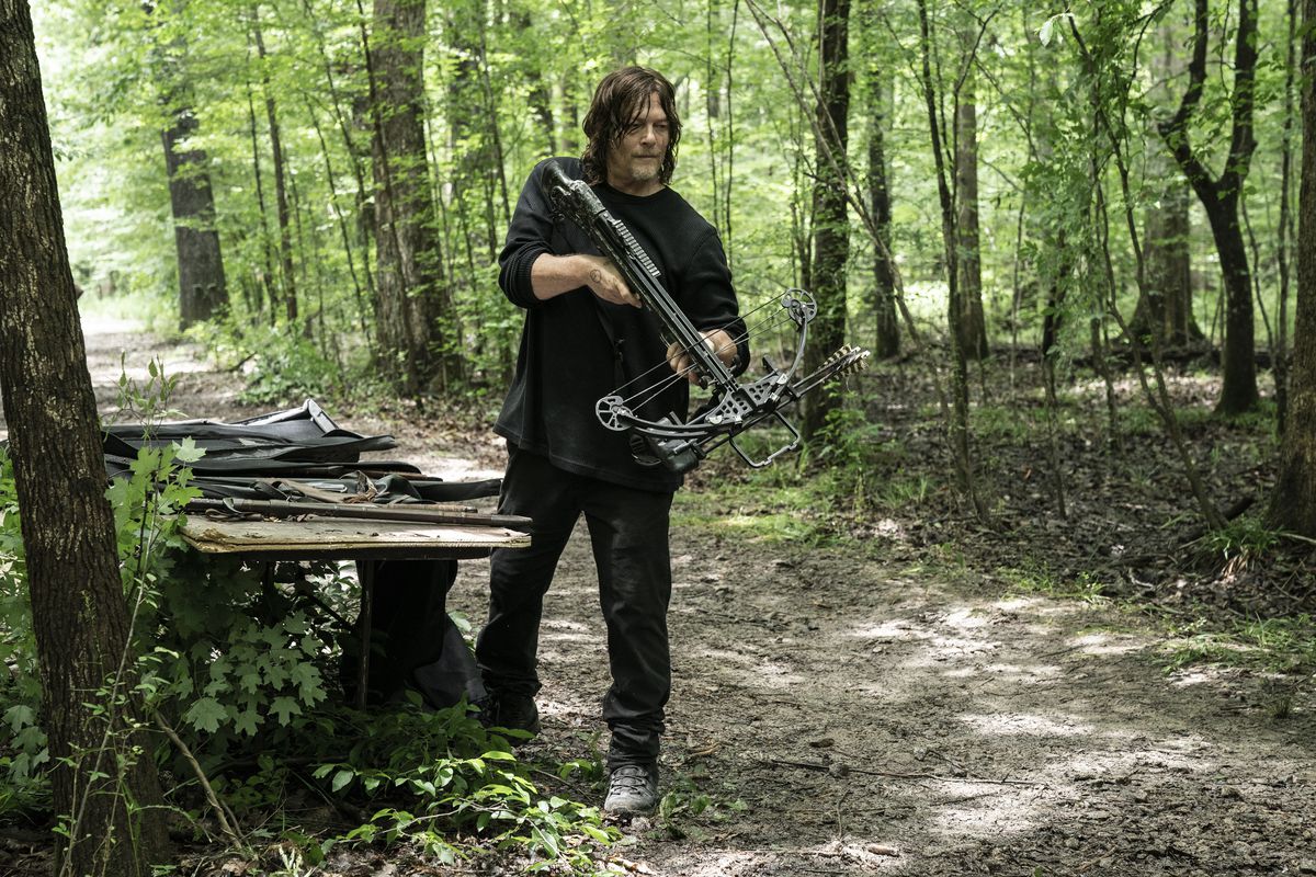 Daryl Dixon holding a crossbow in the woods