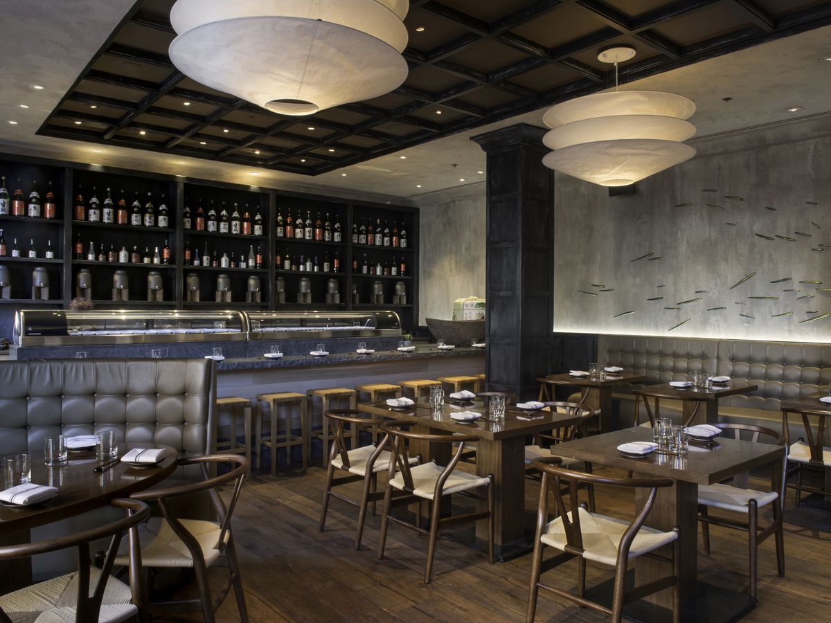 A classy restaurant interior with gray walls and booths, a hardwood floor, and striking round light fixtures
