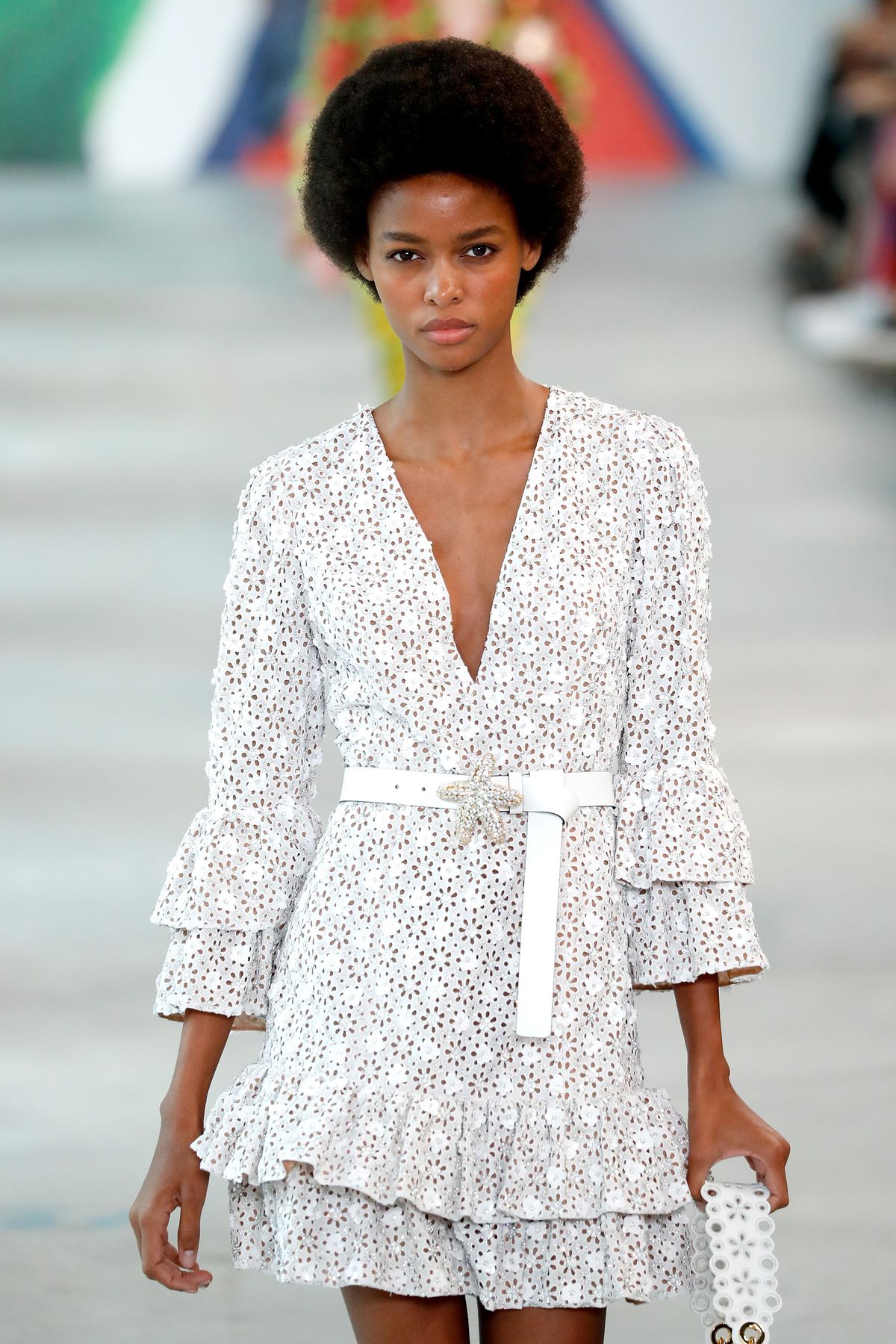 A model wears a frilly white minidress with long bell sleeves.