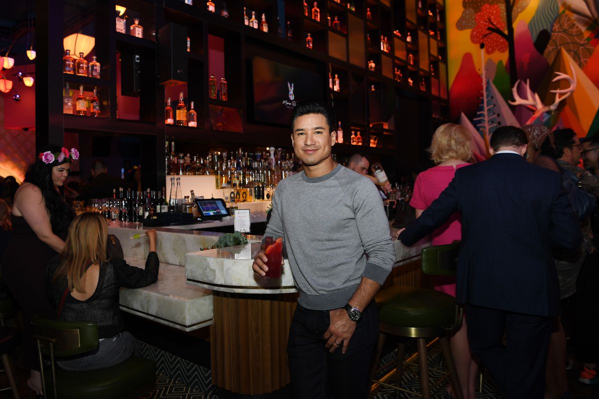 A man stands in front of a bar with a cocktail