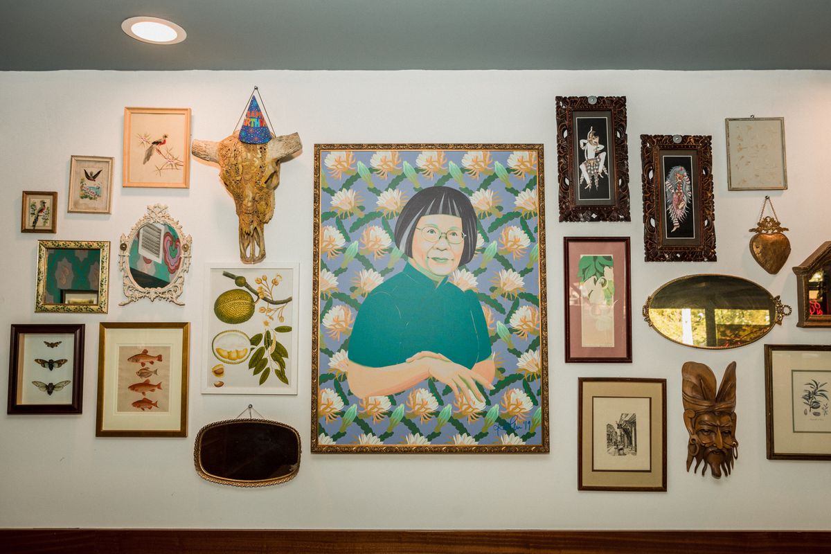 A gallery wall of artwork with a large portrait of a woman at the center