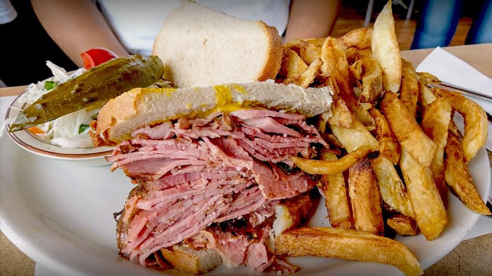 A stuffed smoked meat sandwich with fries on the side.